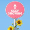 Pink sign with "keep growing" and sunflowers