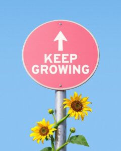 Pink sign with "keep growing" and sunflowers