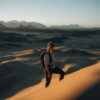 a woman standing on top of a sand dune